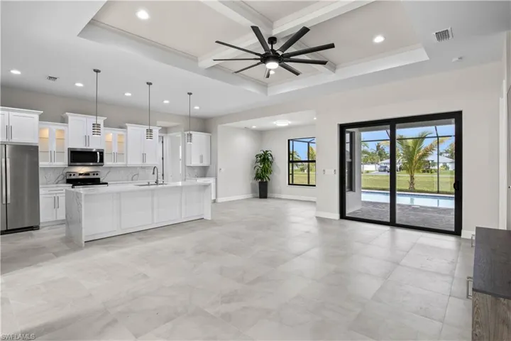 Kitchen featuring ceiling fan, beamed ceiling, a raised ceiling, appliances with stainless steel finishes, and light tile patterned floors