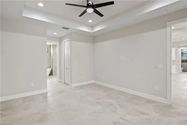 Tiled spare room featuring ceiling fan and a raised ceiling