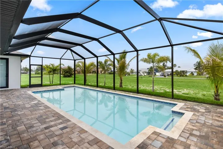 View of pool featuring a patio, a lawn, and glass enclosure