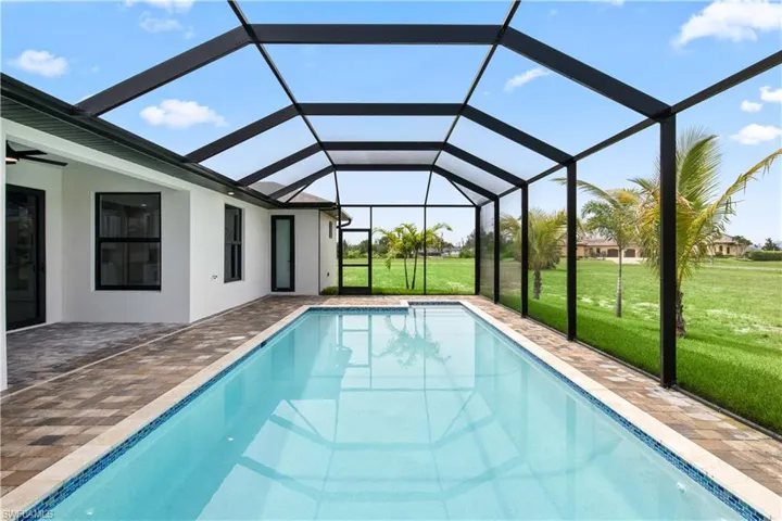 View of pool with a patio, glass enclosure, and a lawn