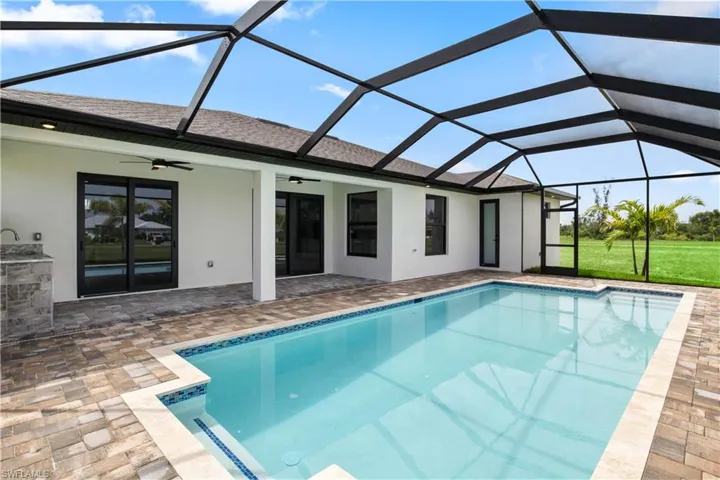 View of pool featuring a patio area, ceiling fan, and glass enclosure