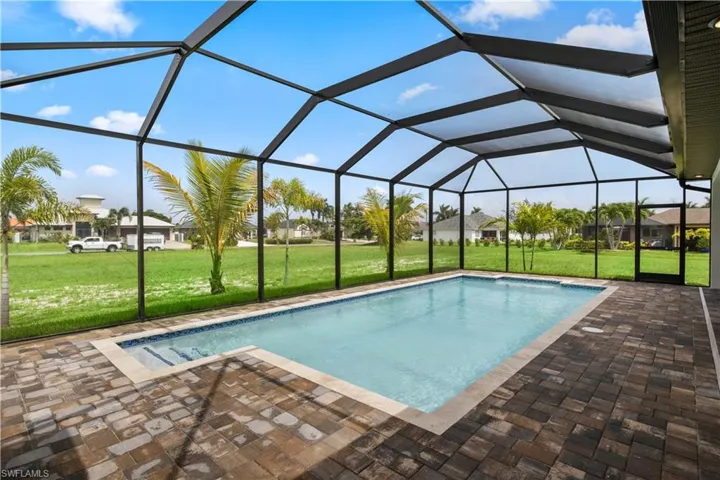 View of swimming pool with a patio, a yard, and glass enclosure