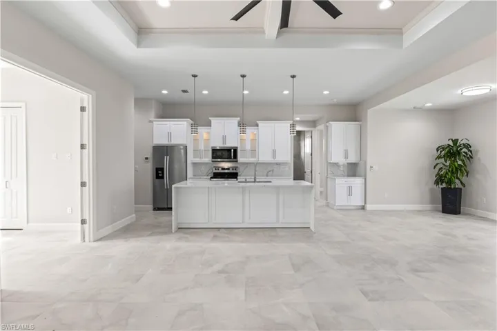 Kitchen featuring light tile patterned flooring, white cabinetry, ceiling fan, a center island with sink, and appliances with stainless steel finishes
