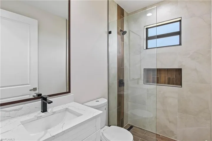Bathroom featuring toilet, vanity, and an enclosed shower