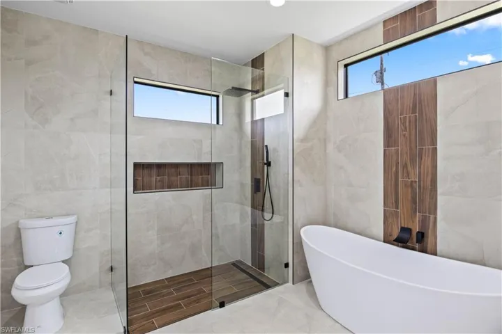 Bathroom featuring independent shower and bath, tile walls, toilet, and tile patterned floors