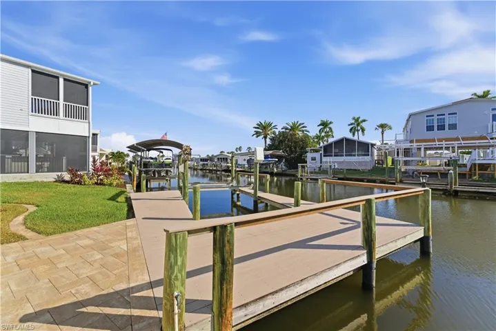 Dock with boat lift, a water view, a sunroom, a residential view, and a yard