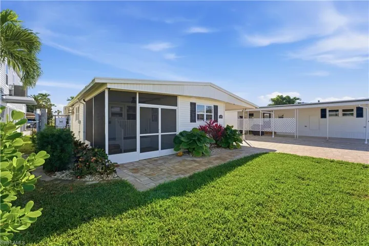 Back of property with a lawn, a patio, and a sunroom