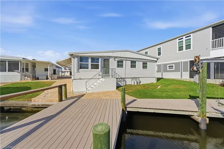 Rear view of property featuring a water view, a lawn, and a sunroom