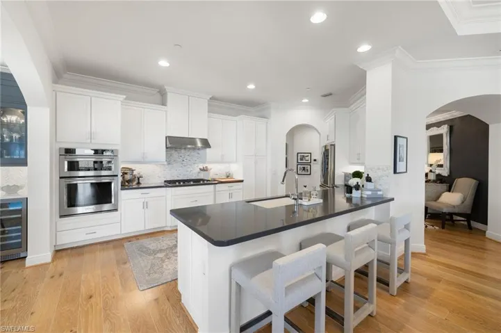 Kitchen with sink, a breakfast bar area, stainless steel appliances, white cabinets, and kitchen peninsula