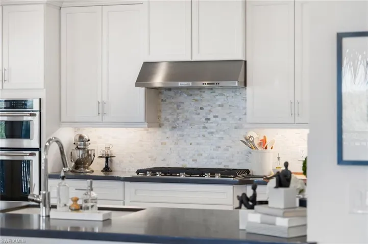 Kitchen with backsplash, stainless steel appliances, sink, and white cabinets