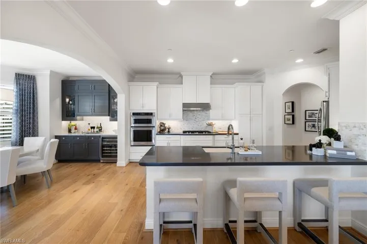 Kitchen with white cabinets, a breakfast bar area, beverage cooler, and kitchen peninsula
