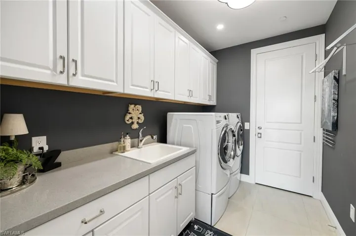 Laundry room featuring cabinets, sink, washer and dryer, and light tile patterned floors