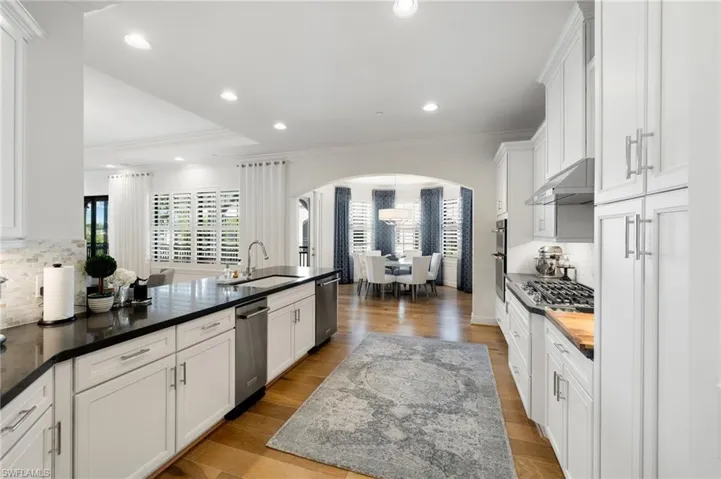 Kitchen with white cabinetry, sink, crown molding, and light hardwood / wood-style flooring