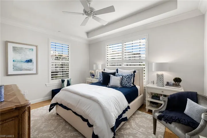 Bedroom with crown molding, ceiling fan, light wood-type flooring, and a tray ceiling