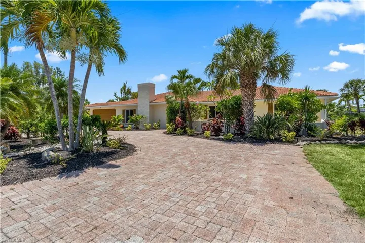 Stunning front elevation with mature landscaping and a spacious circular drive—your private island retreat begins here.
