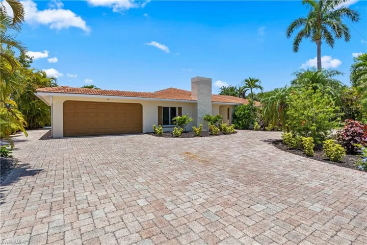 Beautifully landscaped front exterior featuring a welcoming courtyard patio and elegant island-inspired design.