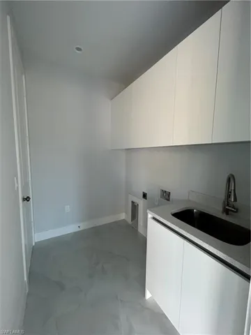 Clothes washing area with cabinets, hookup for a washing machine, electric dryer hookup, and sink