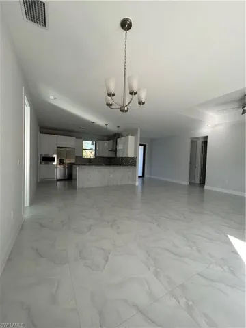 Unfurnished living room featuring an inviting chandelier
