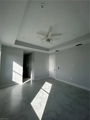 Unfurnished room featuring a tray ceiling and ceiling fan
