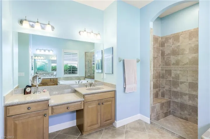Master bathroom featuring tiled shower, 2 vanities, this offers a dressing area, and tile patterned floors