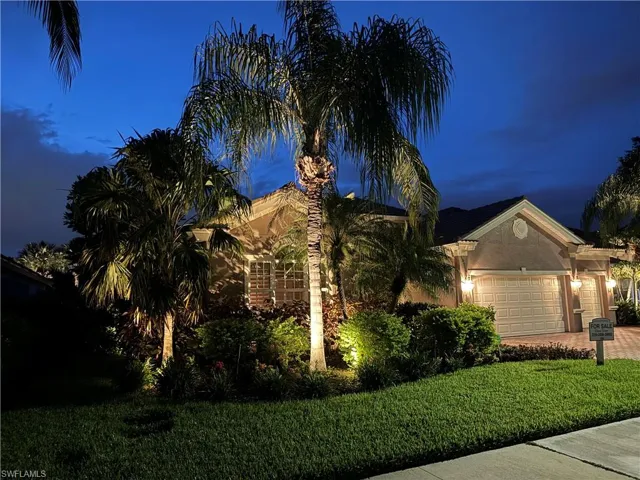 View of front of property with a garage and a yard