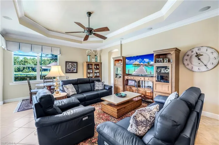 Tiled living room with ceiling fan, crown molding, and a tray ceiling. You have access to your lanai from here as well.