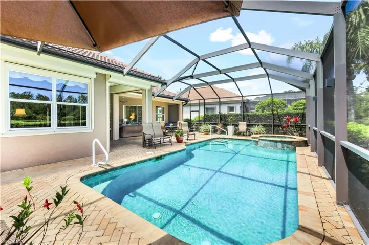 View of swimming pool featuring an in ground hot tub, a patio area, and glass enclosure