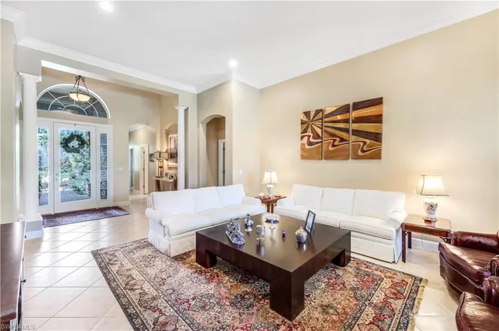 Tiled living room featuring ornamental molding, columns and natural light. Spectacular eyched glass entry door.