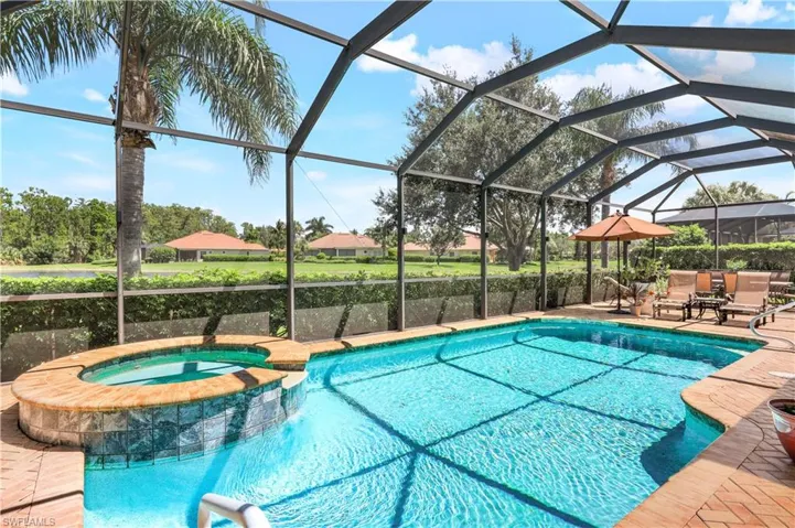 View of swimming pool featuring a patio area, an in ground hot tub, and a lanai overlooking the lake. Pavered deck.