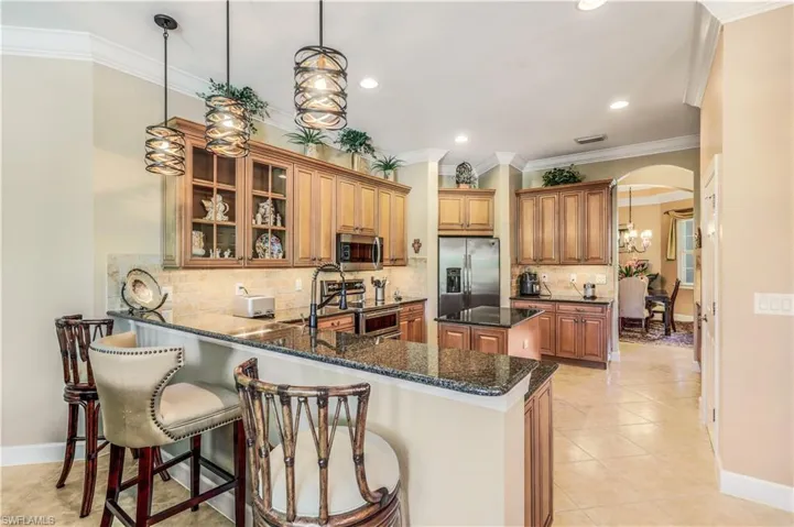 Kitchen featuring light tile patterned flooring laid on the diagonal, decorative backsplash, appliances with stainless steel finishes, and kitchen peninsula. Island, new copper farm sink. Custom pendant lighting.
