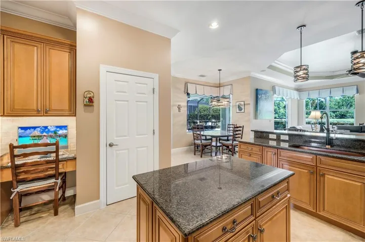 Kitchen featuring new copper sink, hanging light fixtures, light tile patterned floors, a kitchen island, and decorative backsplash. Business nook and pantry.