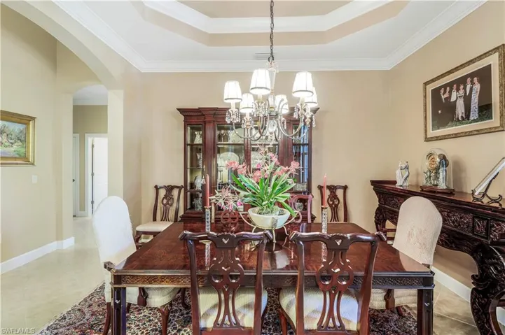 Tiled dining area with a double tray ceiling, crown molding, and an inviting chandelier.