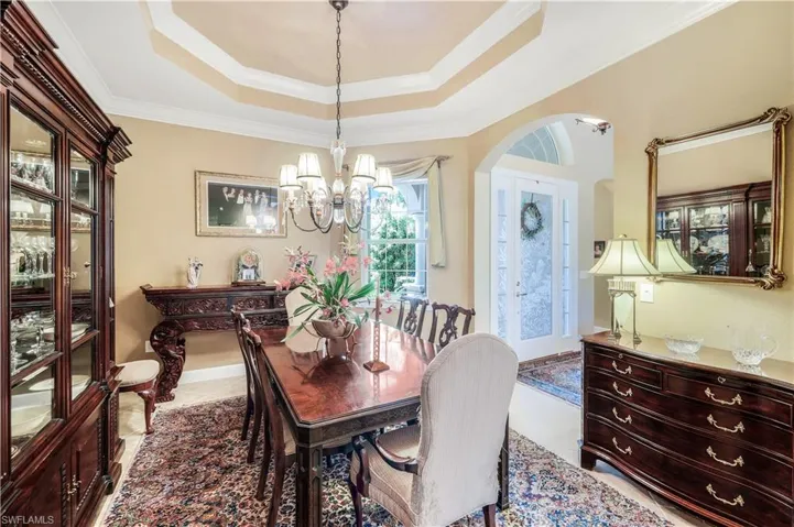 Formal dining room featuring an inviting chandelier, crown molding, and a double tray ceiling.