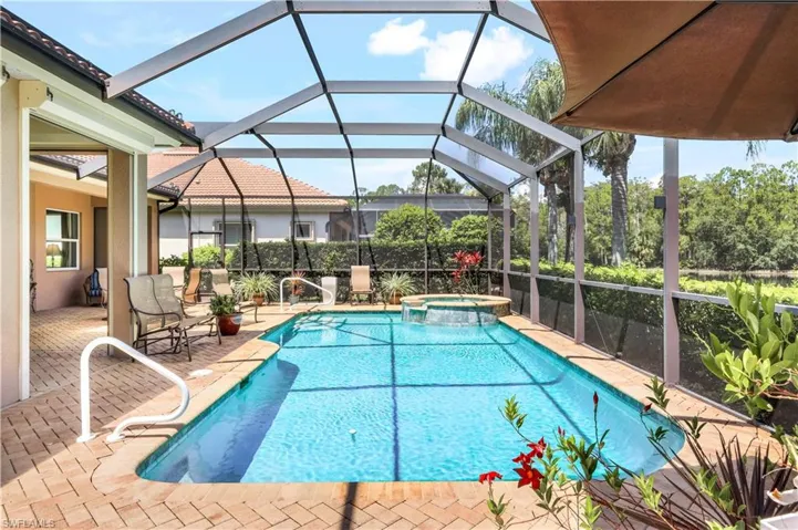 View of swimming pool with an in ground hot tub, a patio, and glass enclosure