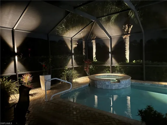 Pool at night with a patio, pool, spa, and screen enclosure