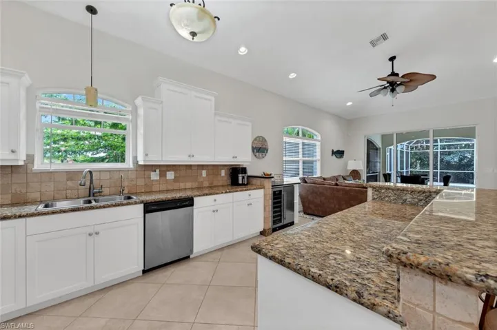 Kitchen featuring sink, stainless steel dishwasher, decorative backsplash, and white cabinets