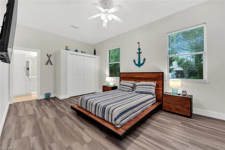 Bedroom with light hardwood / wood-style floors, multiple windows, ceiling fan, and a closet