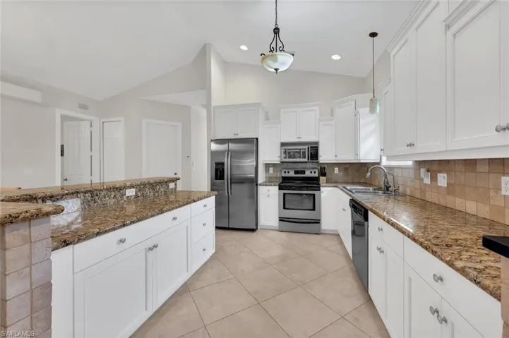 Kitchen featuring appliances with stainless steel finishes, sink, decorative light fixtures, decorative backsplash, and lofted ceiling