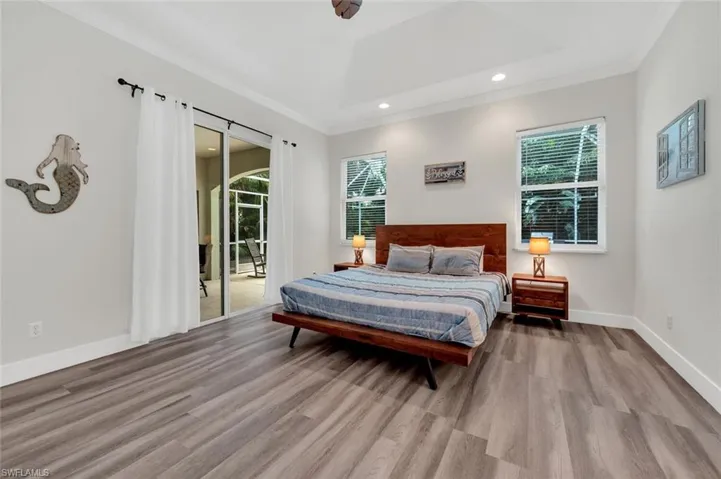 Bedroom with multiple windows, hardwood / wood-style flooring, and a raised ceiling