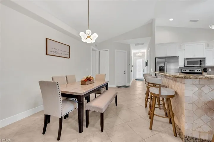 Tiled dining room featuring an inviting chandelier and vaulted ceiling