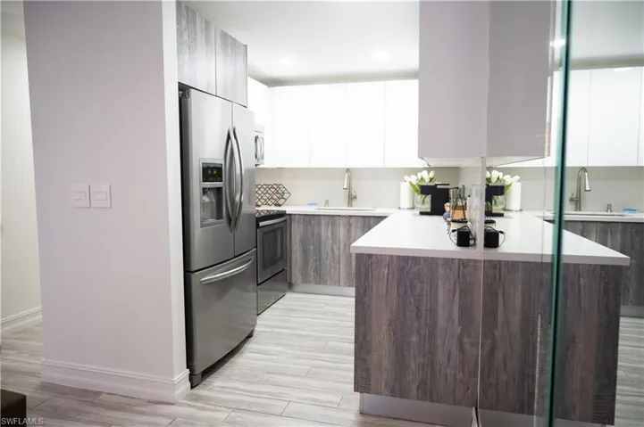 Kitchen featuring dual tone cabinetry, modern cabinets, stainless steel appliances, wood tiled floors, and recessed lighting