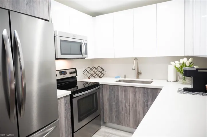 Kitchen featuring stainless steel appliances, two tone cabinets, and modern cabinets