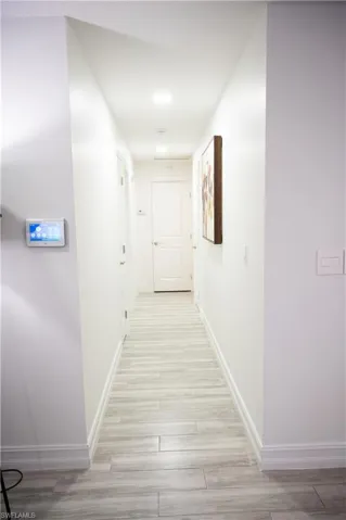 Hallway featuring light wood finished floors and baseboards