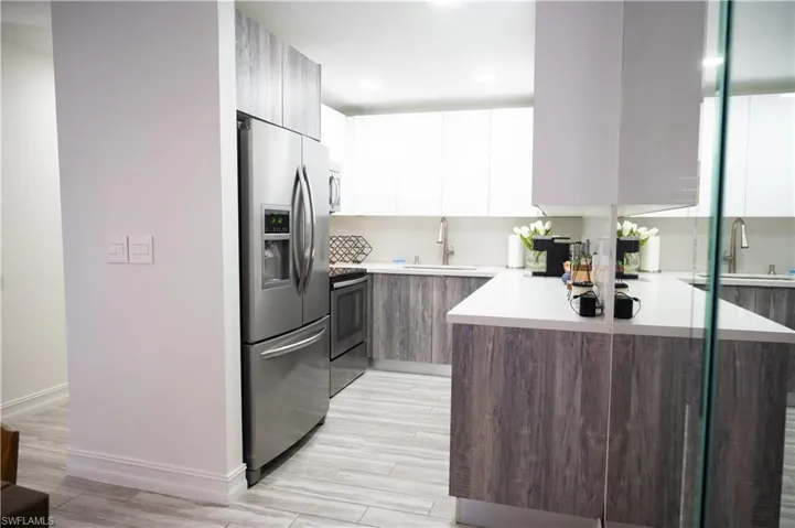 Dual tone kitchen with two tone color scheme, modern cabinets, stainless steel appliances, wood tiled floors, and recessed lighting