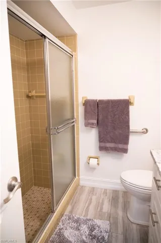 Bathroom featuring vanity, a shower stall, and light wood-style floors