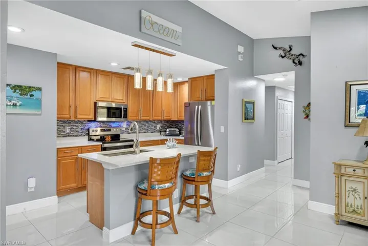 Kitchen featuring wood finish cabinets, a kitchen breakfast bar, stainless steel appliances, and light tile patterned floors