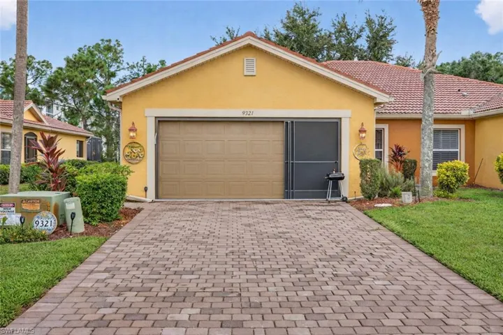 Ranch-style house with stucco siding, decorative driveway, a front lawn, an attached garage, and a tiled roof