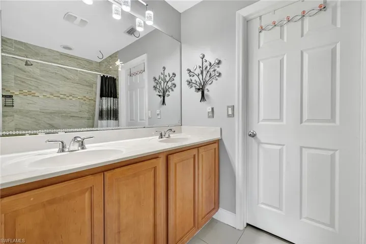 Full bath featuring double vanity, a tile shower, and light tile patterned floors