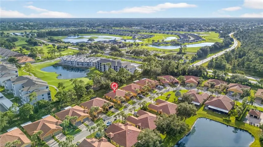 Aerial view of property and surrounding area featuring a nearby body of water, a local golf course, and nearby suburban area