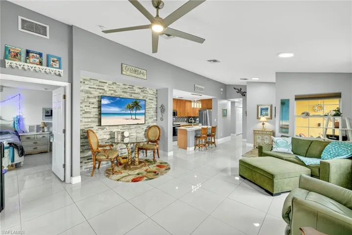 Living room with ceiling fan, light tile patterned floors, and vaulted ceiling
